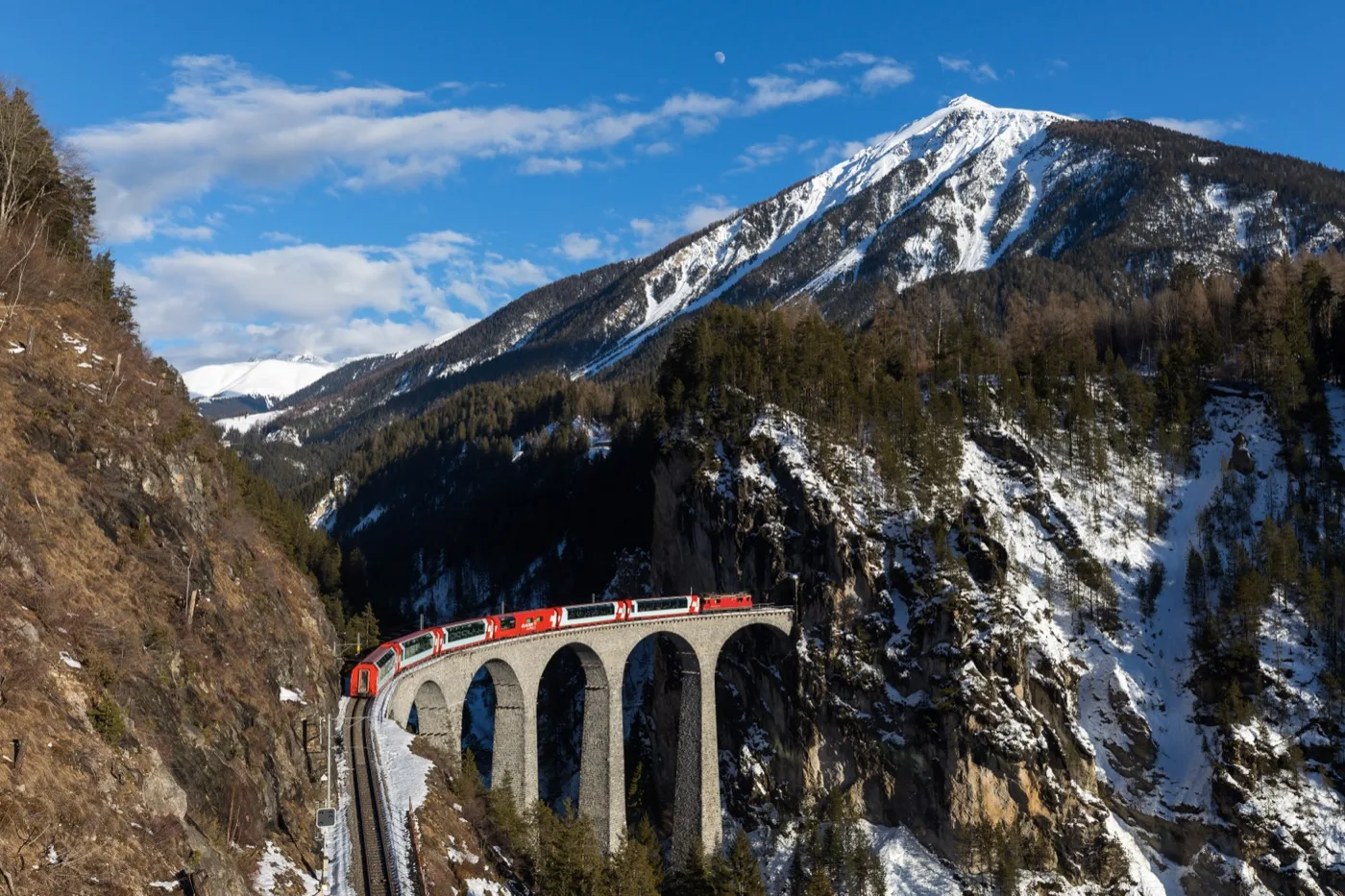 A red Rhaetian Railway train crossing the Landwasser Viaduct